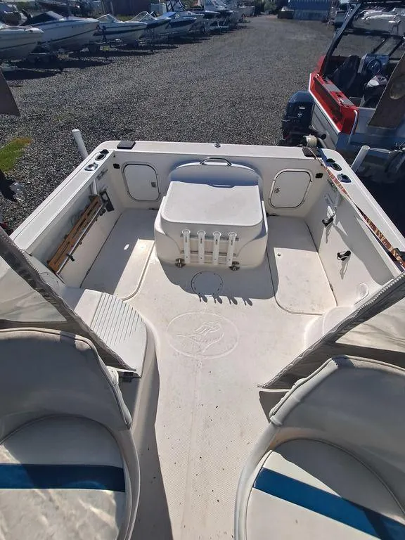 Slide: The Image of 1998 Bayliner 2052 boat interior with seating and storage, parked on gravel. - 7