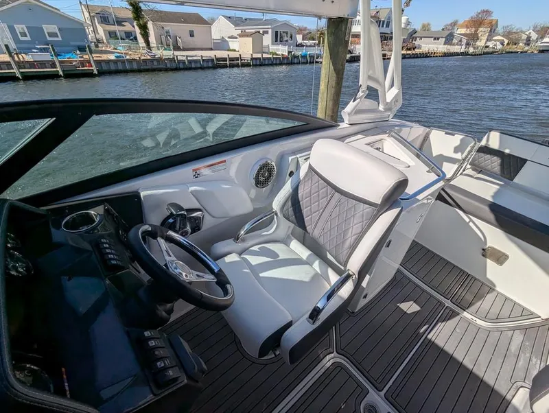 Slide: The Image of 2023 Monterey M-65 boat interior with steering wheel and seating, docked by waterfront homes. - 14