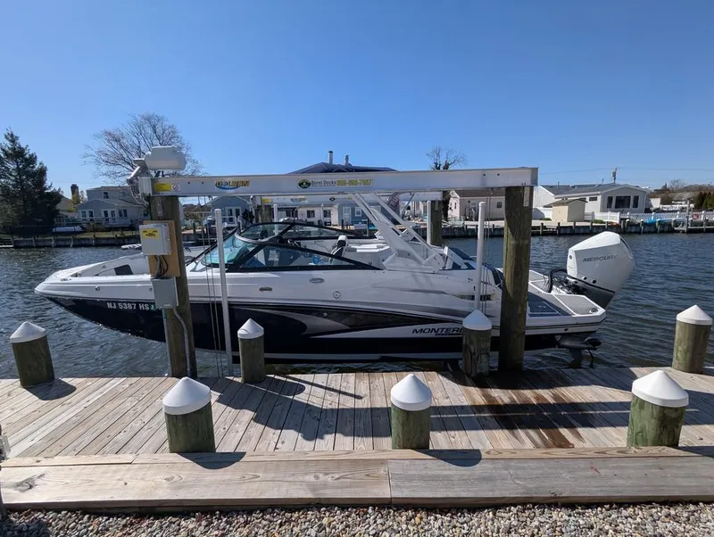 Slide: The Image of 2023 Monterey M-65 boat docked at a marina under clear blue skies. - 2