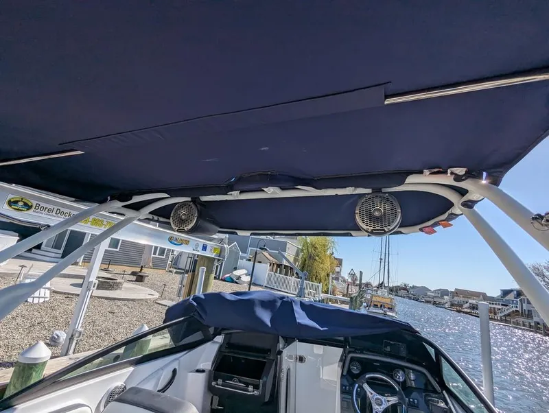 Slide: The Image of 2023 Monterey M-65 boat interior with canopy and speakers, docked by a waterfront. - 26