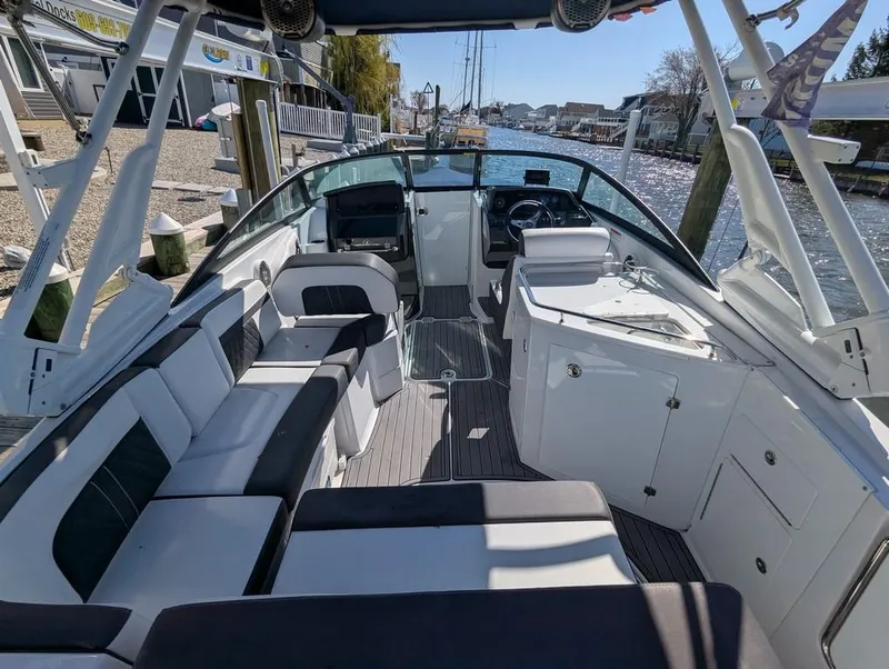 Slide: The Image of 2023 Monterey M-65 boat interior with seating, docked by a waterfront. - 45