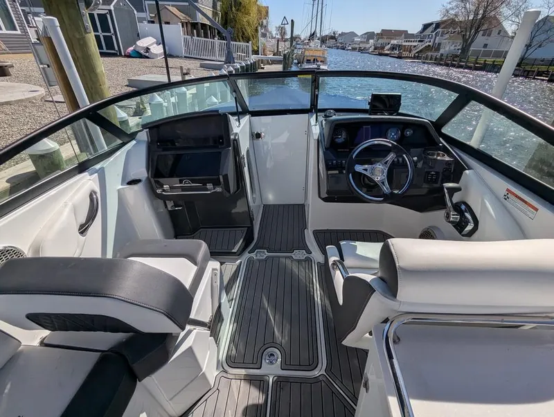Slide: The Image of 2023 Monterey M-65 boat interior with sleek seating and modern dashboard, docked by a canal. - 46