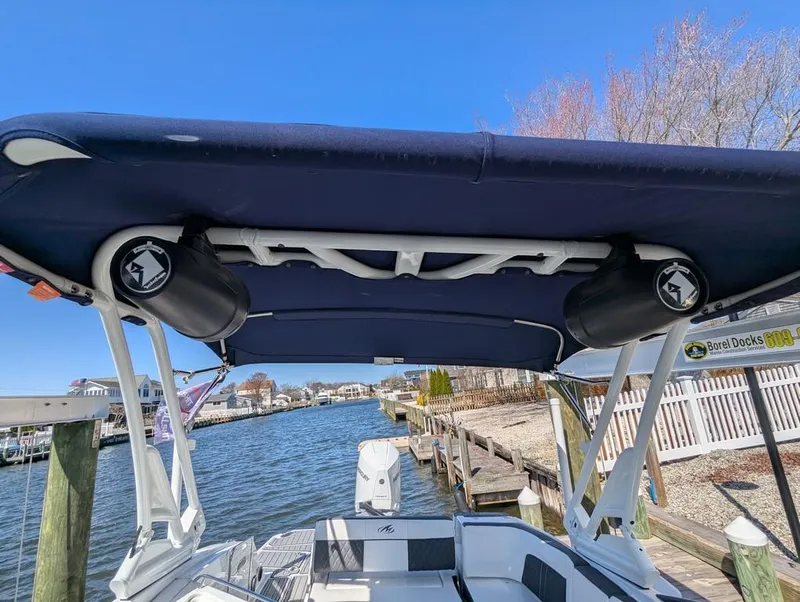 Slide: The Image of 2023 Monterey M-65 boat with canopy and speakers, docked by a scenic waterfront. - 48