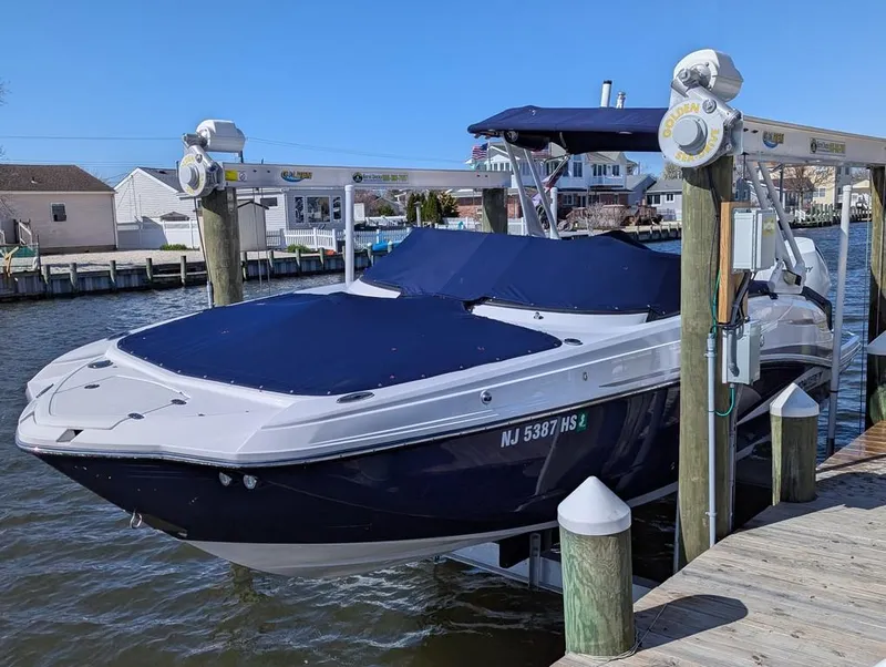 Slide: The Image of 2023 Monterey M-65 boat docked, covered in blue, with waterfront homes in the background. - 6