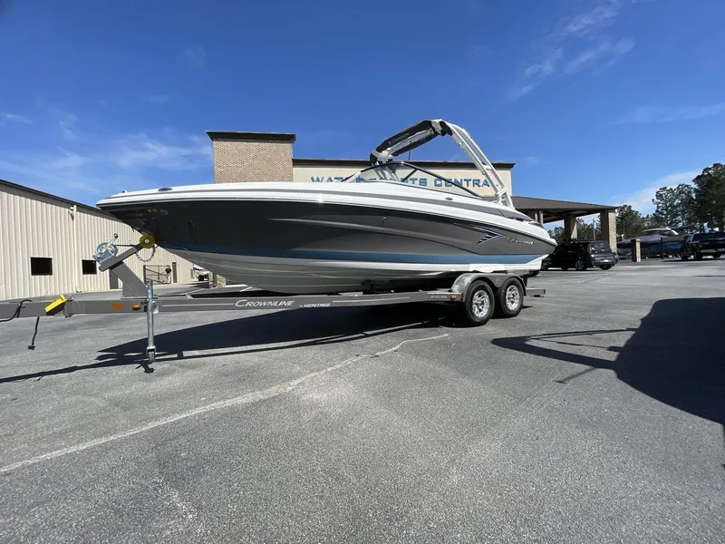 Slide: The Image of 2023 Crownline 240 SS boat on trailer, parked outdoors under clear blue sky. - 0
