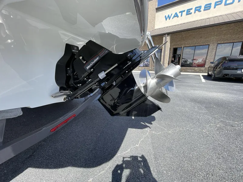 Slide: The Image of 2023 Crownline 240 SS boat propeller and outdrive in a parking lot near a watersports store. - 13
