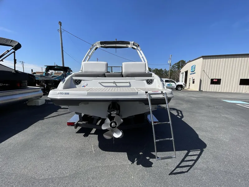 Slide: The Image of 2023 Crownline 240 SS boat, rear view with ladder, parked outdoors under clear sky. - 8