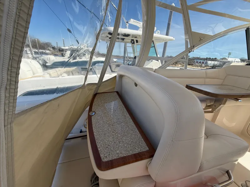 Slide: The Image of 2015 Grady-White Freedom 335 boat interior with cushioned seating and table, showcasing luxury design. - 12