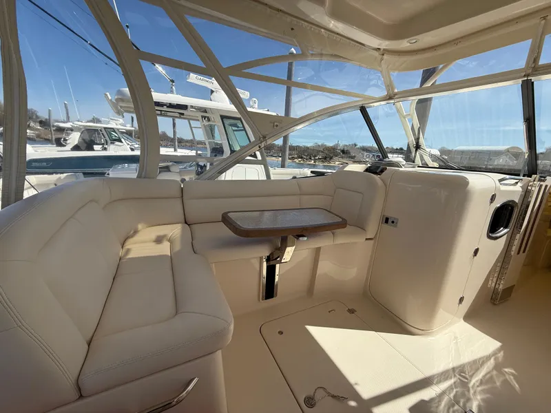 Slide: The Image of 2015 Grady-White Freedom 335 boat interior with seating and table, featuring a bright, spacious cabin. - 13