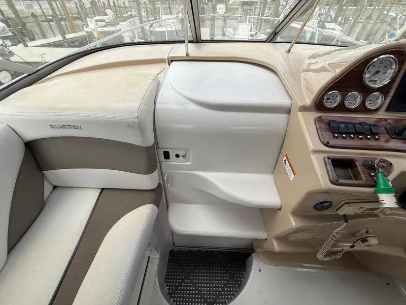 Slide: The Image of 2014 Glastron GS 289 boat interior with beige and white seating, dashboard, and controls. - 28