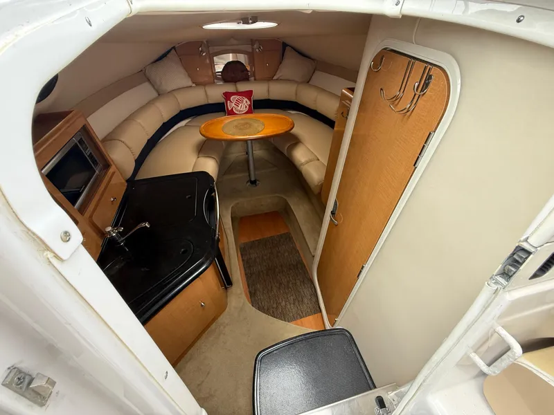 Slide: The Image of 2014 Glastron GS 289 cabin interior with seating, table, and kitchenette. - 29