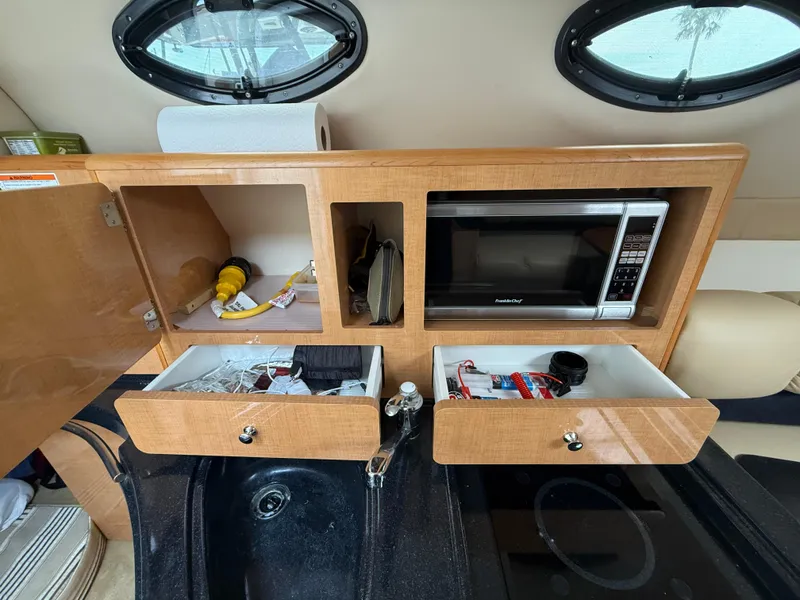 Slide: The Image of 2014 Glastron GS 289 boat interior with kitchenette, microwave, and storage drawers. - 47