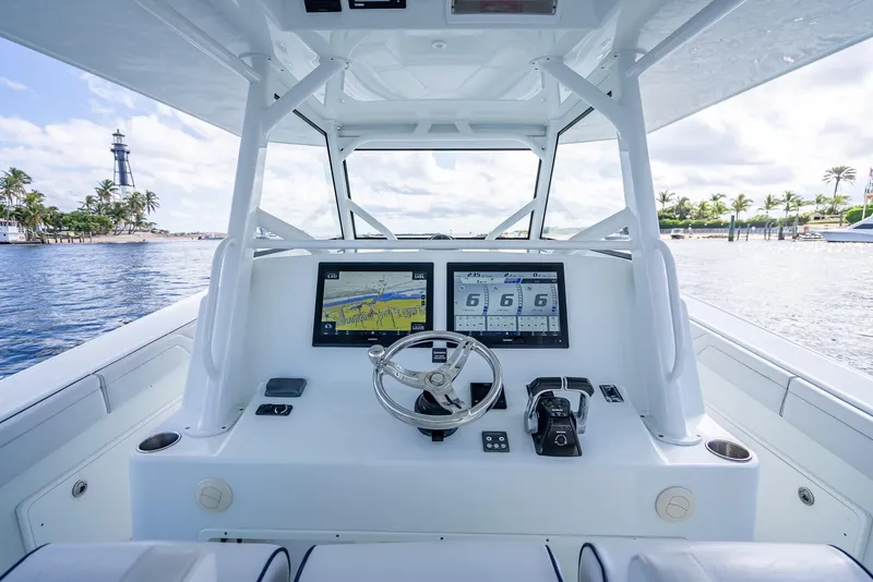 Slide: The Image of 2018 Yellowfin 42 boat helm with dual navigation screens, steering wheel, and ocean view. - 20