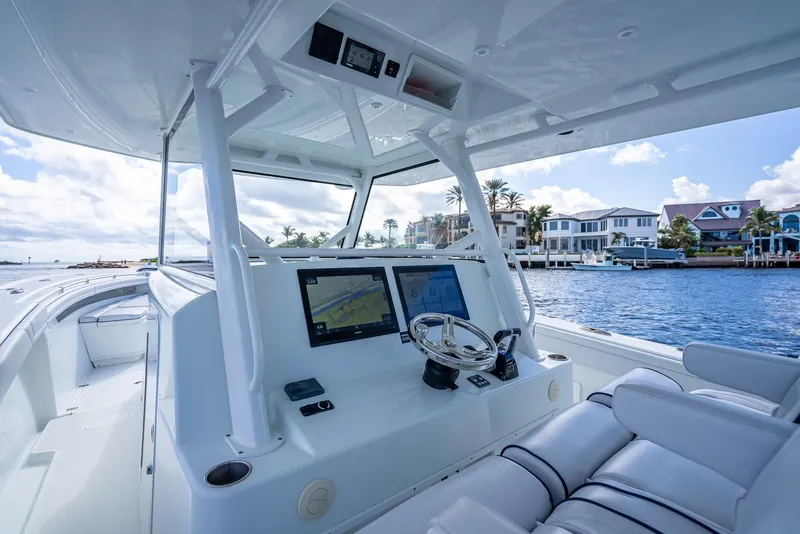 Slide: The Image of 2018 Yellowfin 42 boat cockpit with dual screens, steering wheel, and waterfront view. - 23