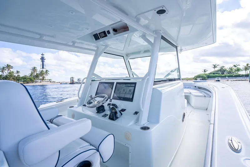 Slide: The Image of 2018 Yellowfin 42 boat interior with modern controls, near tropical island and lighthouse. - 24