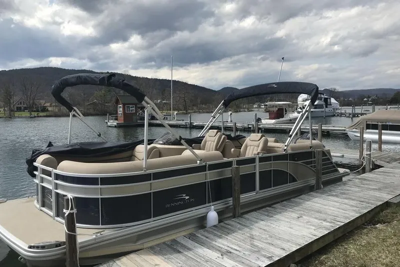 Slide: The Image of 2018 Bennington 23GSRFB pontoon boat docked by a scenic lake with mountains. - 0