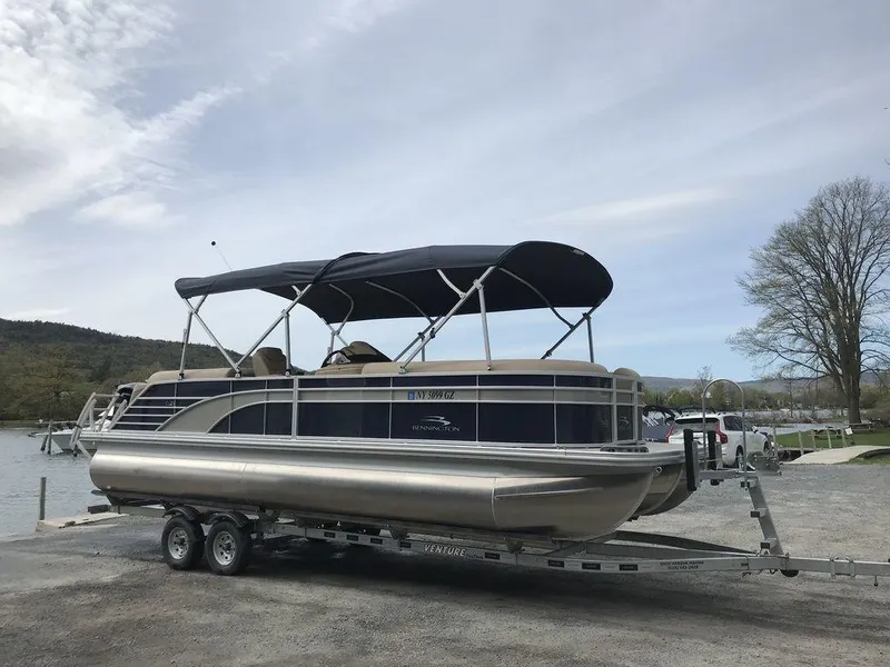 Slide: The Image of 2018 Bennington 23GSRFB pontoon boat on trailer by a lake. - 1