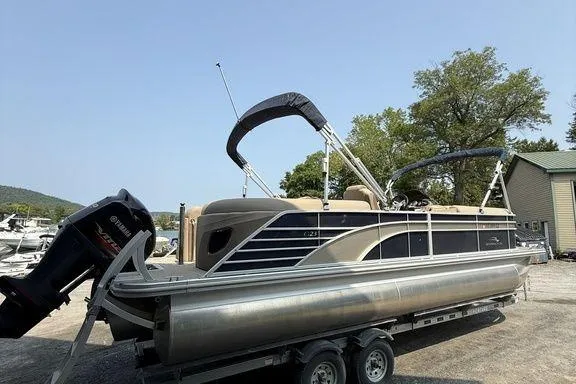 Slide: The Image of 2018 Bennington 23GSRFB pontoon boat on trailer, featuring a sleek design and powerful outboard motor. - 2