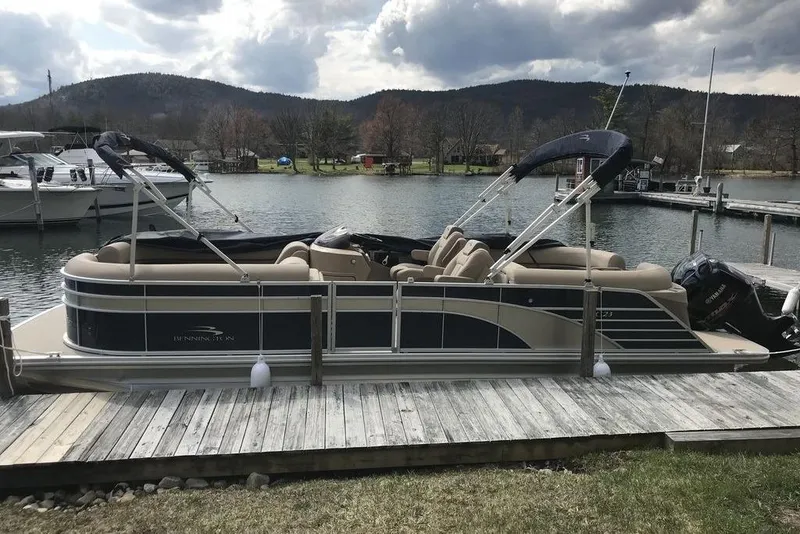 Slide: The Image of 2018 Bennington 23GSRFB pontoon boat docked by a scenic lake with hills in the background. - 9
