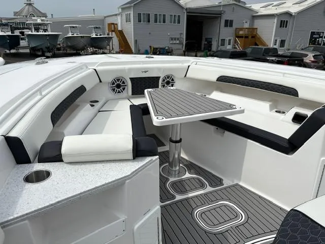 Slide: The Image of 2025 Tidewater 380 CC Adventure boat interior with seating and table, docked near buildings. - 11