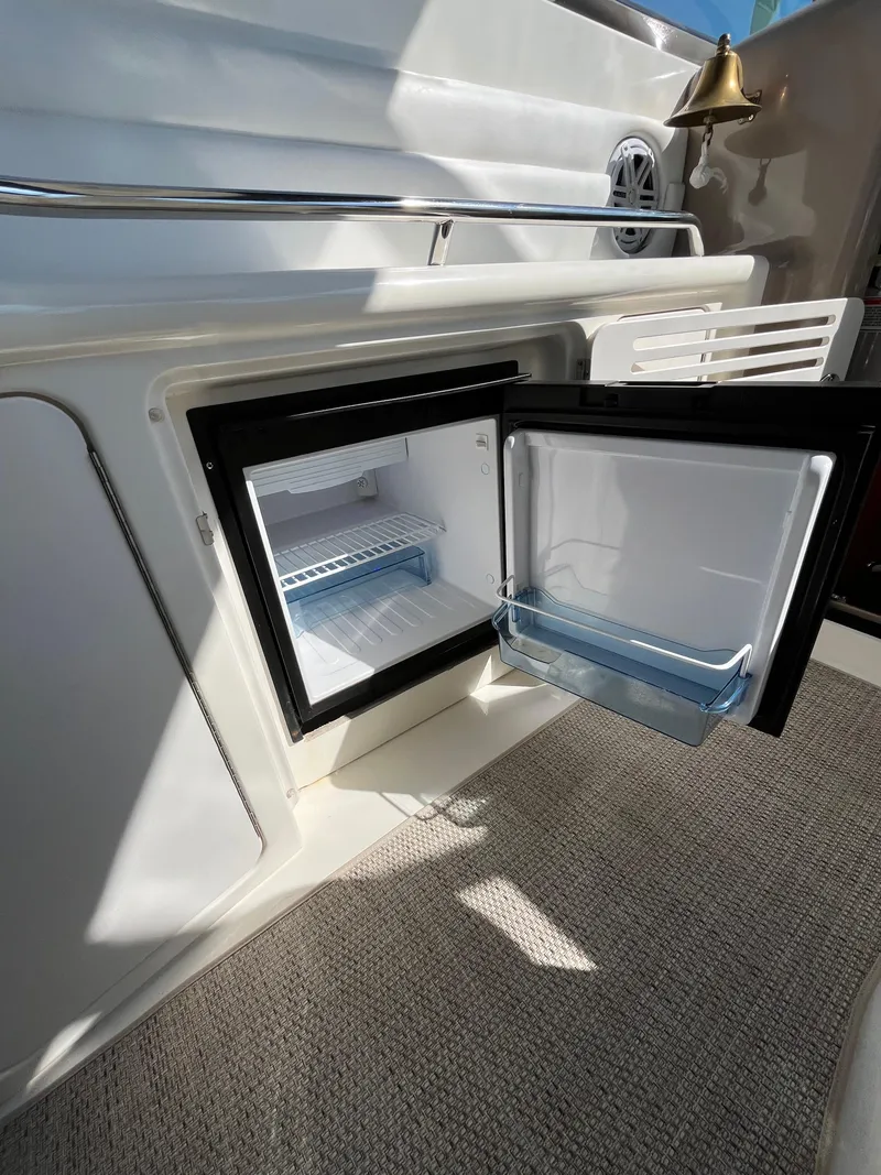 Slide: The Image of Open mini fridge on 2003 Sea Ray 380 Sundancer yacht, showcasing interior storage space. - 18