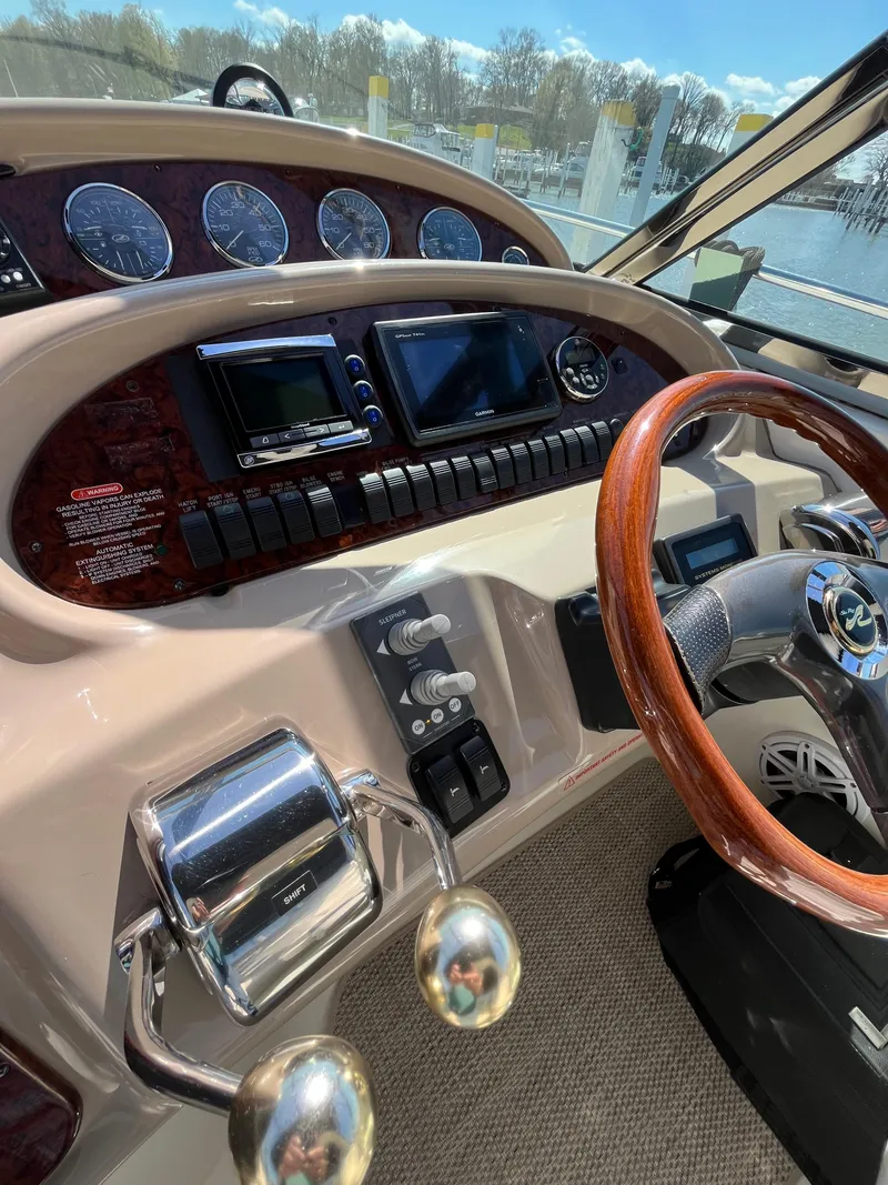 Slide: The Image of 2003 Sea Ray 380 Sundancer helm with gauges, controls, and wooden steering wheel. - 21