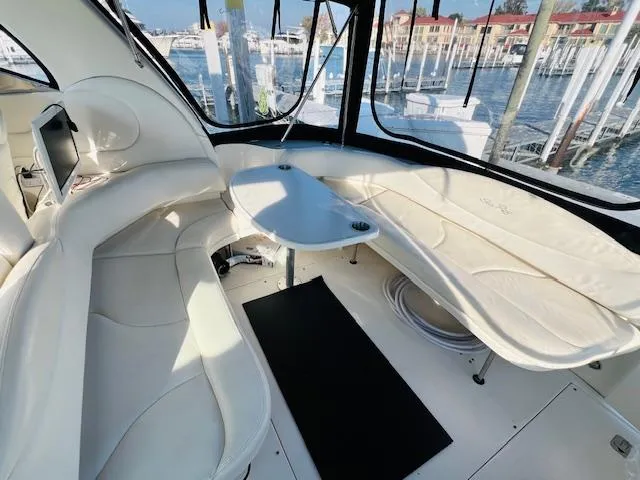 Slide: The Image of 2003 Sea Ray 380 Sundancer cockpit with white seating and table, overlooking marina. - 5