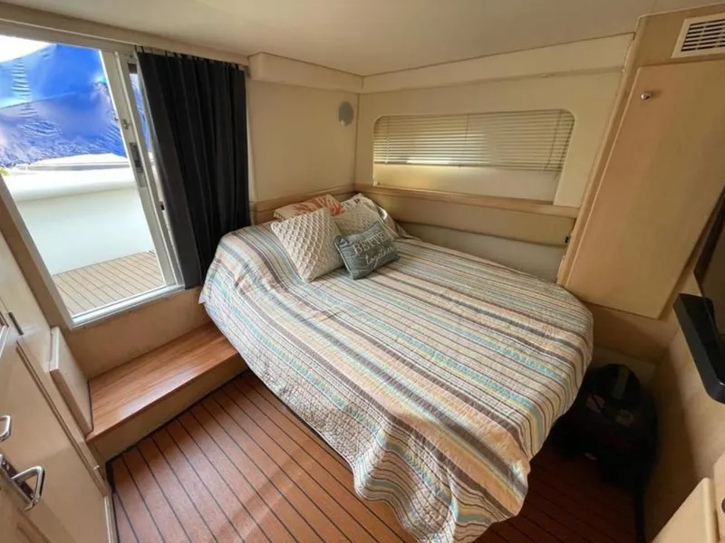 Slide: The Image of Cozy bedroom in 1997 Carver 400 Cockpit Motor Yacht with striped bedding and wooden flooring. - 15