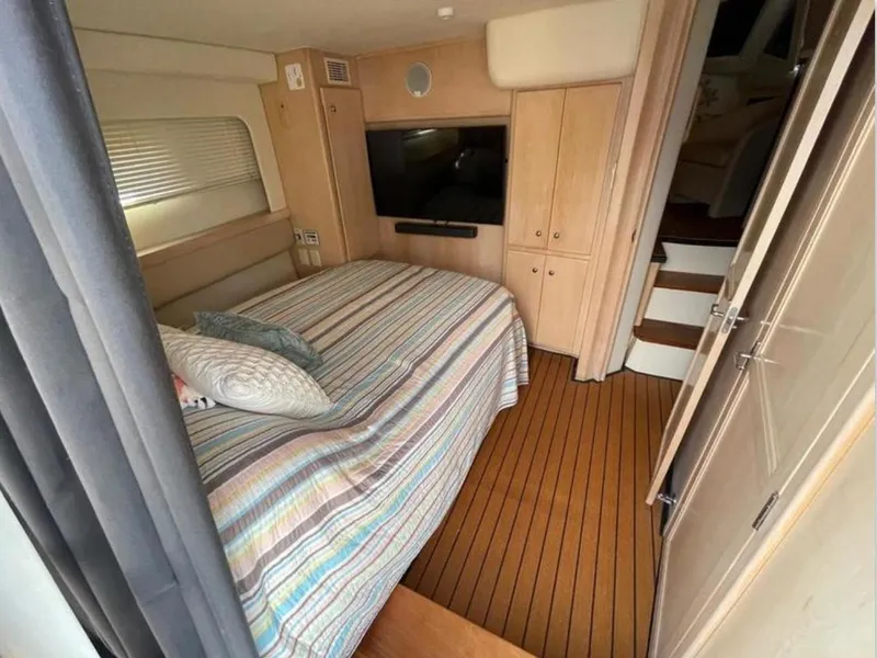 Slide: The Image of 1997 Carver 400 Cockpit Motor Yacht bedroom with striped bedding and wood flooring. - 4