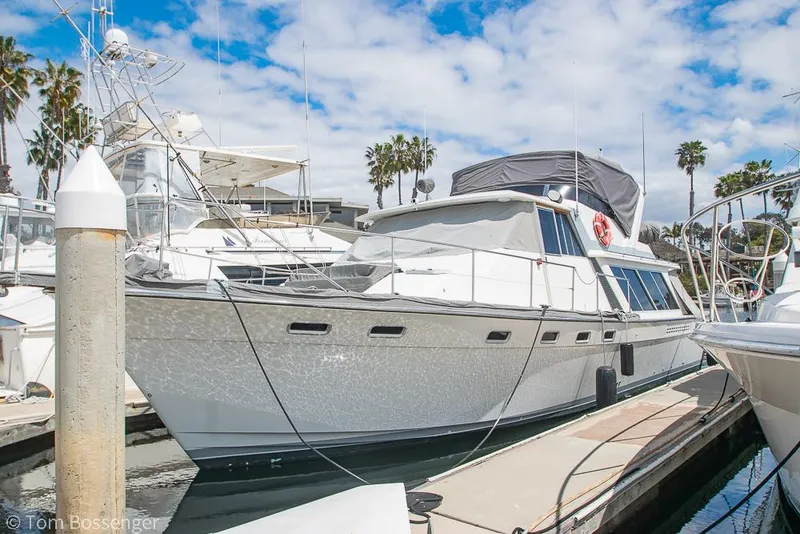 The Image of 1986 Bayliner 4588 Pilothouse yacht docked at marina under blue sky. - 0