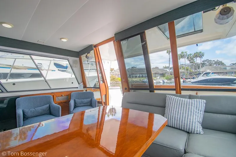 Slide: The Image of Interior of 1986 Bayliner 4588 Pilothouse with wooden table, blue chairs, and marina view. - 13