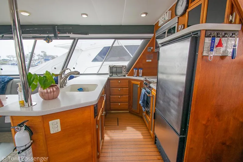 Slide: The Image of 1986 Bayliner 4588 Pilothouse kitchen with wood cabinetry, modern appliances, and potted plant. - 14