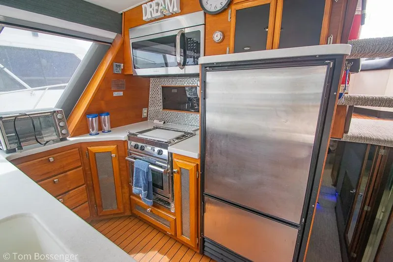 Slide: The Image of 1986 Bayliner 4588 Pilothouse kitchen with stainless appliances, wooden cabinets, and stairs. - 16