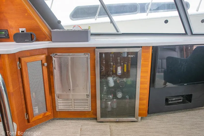 Slide: The Image of 1986 Bayliner 4588 Pilothouse interior with mini fridge and wooden cabinetry. - 18