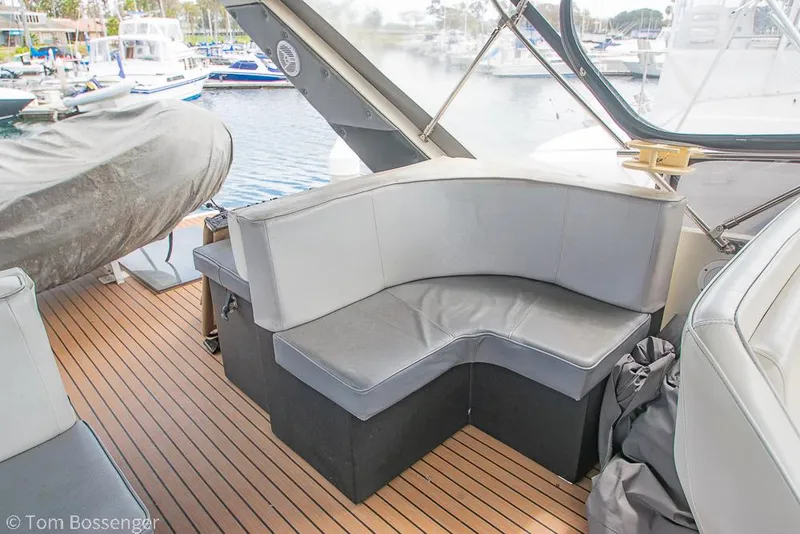 Slide: The Image of 1986 Bayliner 4588 Pilothouse boat with gray seating on a wooden deck at a marina. - 49