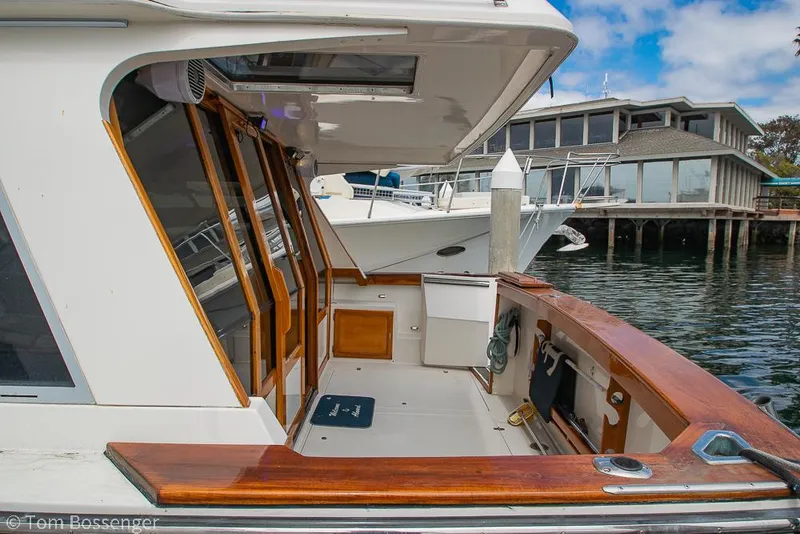 Slide: The Image of 1986 Bayliner 4588 Pilothouse yacht docked, featuring wooden accents and marina backdrop. - 6