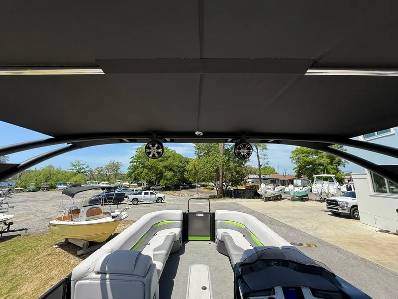Slide: The Image of 2017 Crest Caliber 230 SLR2 pontoon boat interior with canopy and seating, docked outdoors. - 23