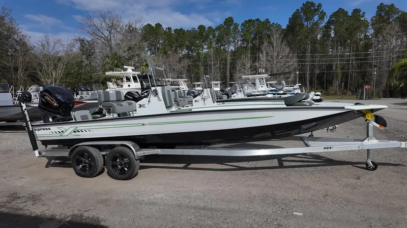 Slide: The Image of 2025 Xpress H24B boat on trailer, parked outdoors with trees in background. - 11