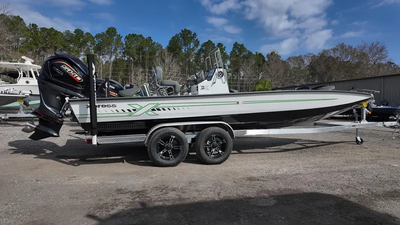 Slide: The Image of 2025 Xpress H24B boat with trailer, parked outdoors under a blue sky. - 12