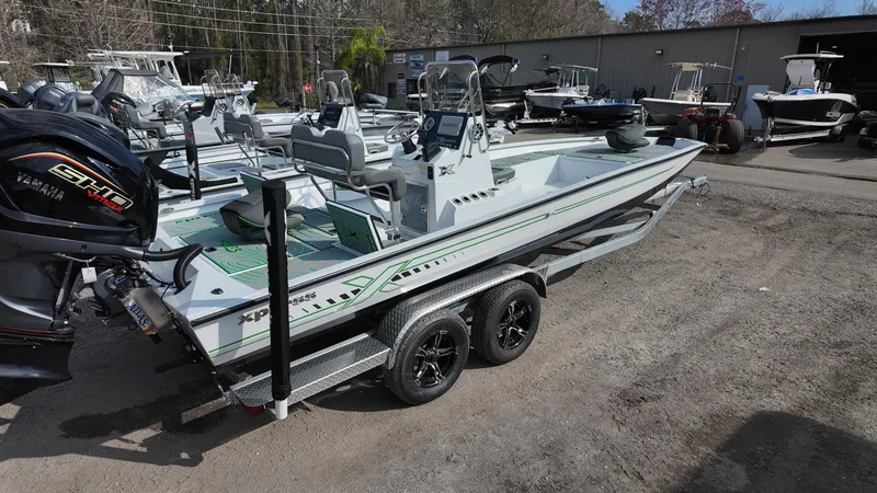 Slide: The Image of 2025 Xpress H24B boat on trailer, parked outdoors with other boats. - 16