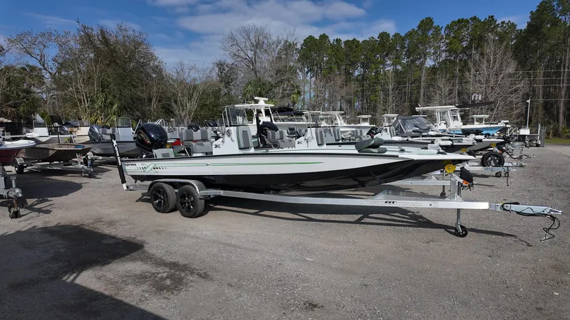 Slide: The Image of 2025 Xpress H24B boat on trailer in outdoor lot, surrounded by trees and other boats. - 9