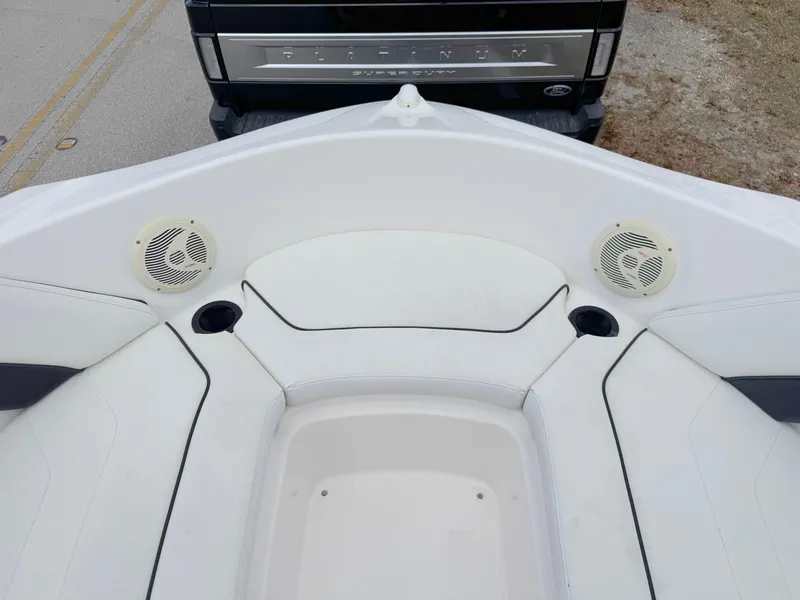 Slide: The Image of 2015 Yamaha Boats SX190 interior with white seating and speakers, parked near a vehicle. - 10