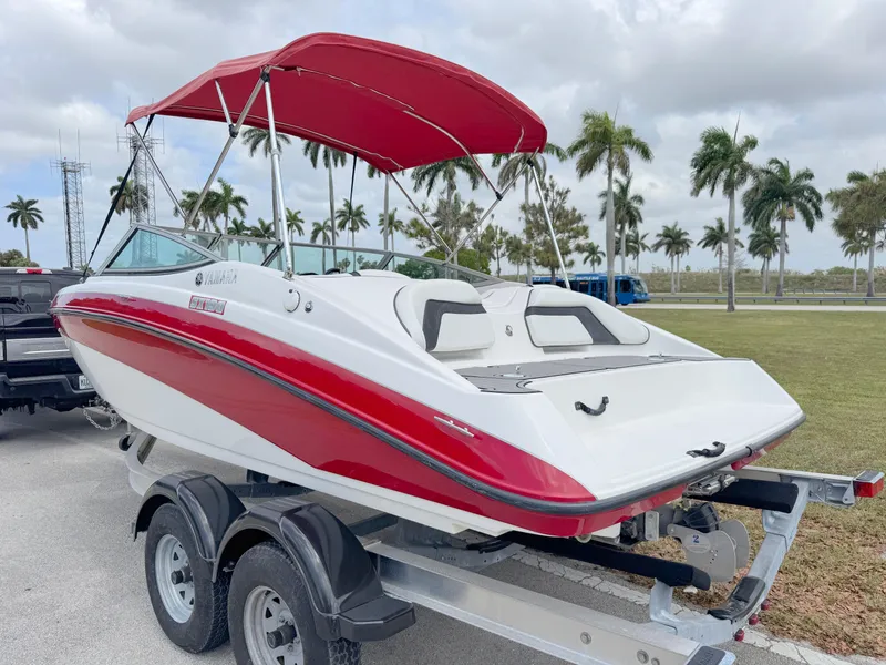 Slide: The Image of 2015 Yamaha SX190 boat with red canopy on trailer, parked near palm trees. - 3