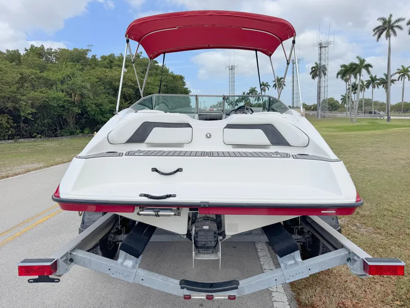 Slide: The Image of 2015 Yamaha Boats SX190 with red canopy on trailer, parked on road. - 4