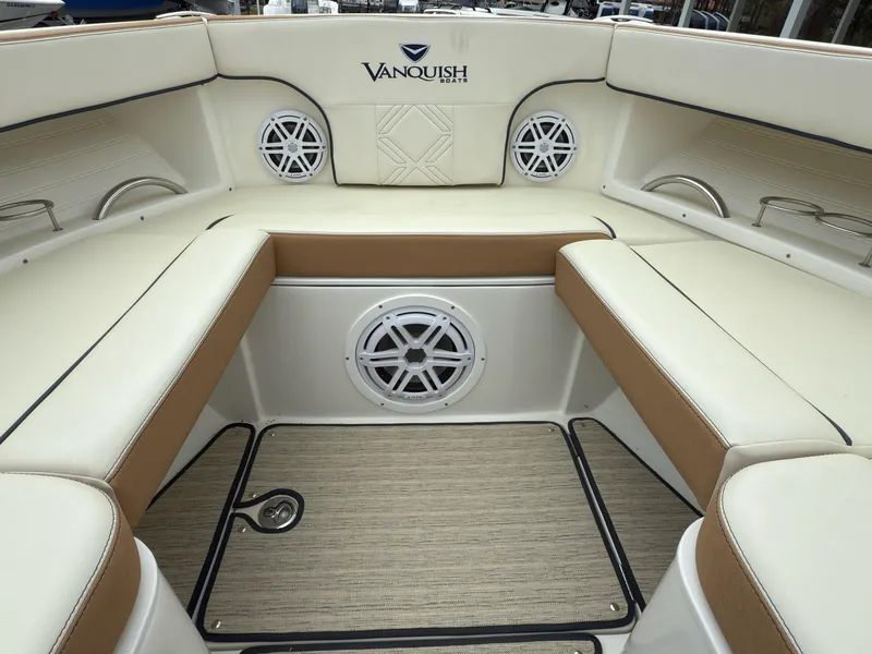 Slide: The Image of 2016 Vanquish 26 DC boat interior with beige seating and speaker system. - 10