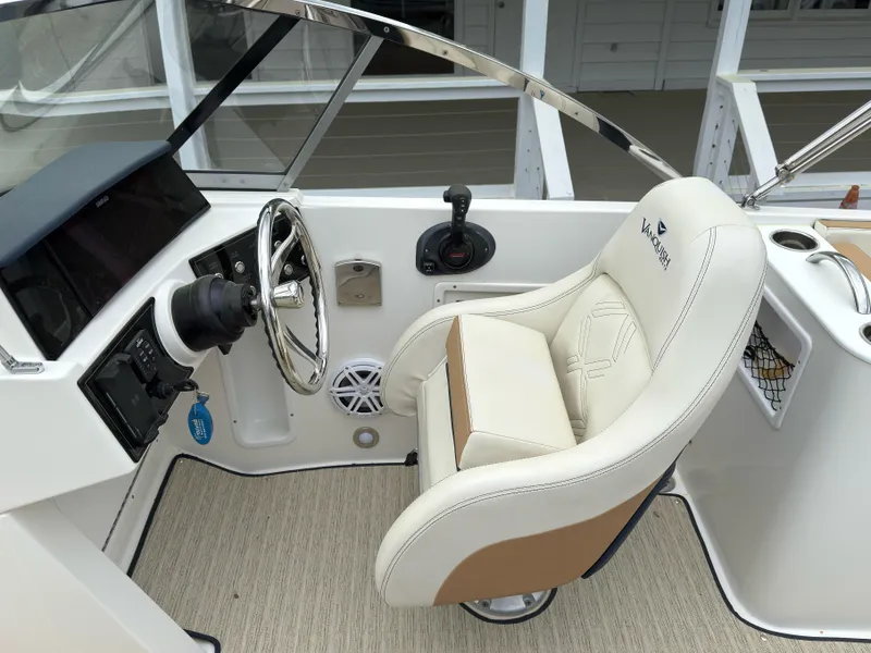 Slide: The Image of 2016 Vanquish 26 DC boat cockpit with steering wheel and beige captain's seat. - 13