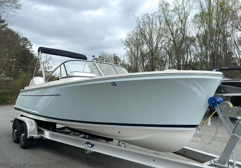 Slide: The Image of 2016 Vanquish 26 DC boat on trailer, parked outdoors under cloudy sky. - 18