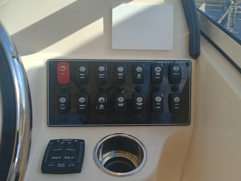 Slide: The Image of Control panel of 2024 Grady-White Freedom 235 boat with various switches and trim tab controls. - 19