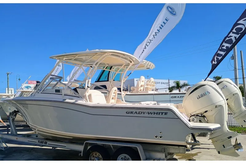 Slide: The Image of 2024 Grady-White Freedom 235 boat on trailer, featuring dual Yamaha engines. - 2