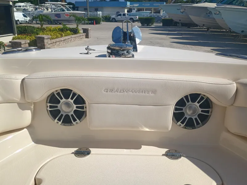 Slide: The Image of 2024 Grady-White Freedom 235 boat interior with speakers and seating in a marina setting. - 6